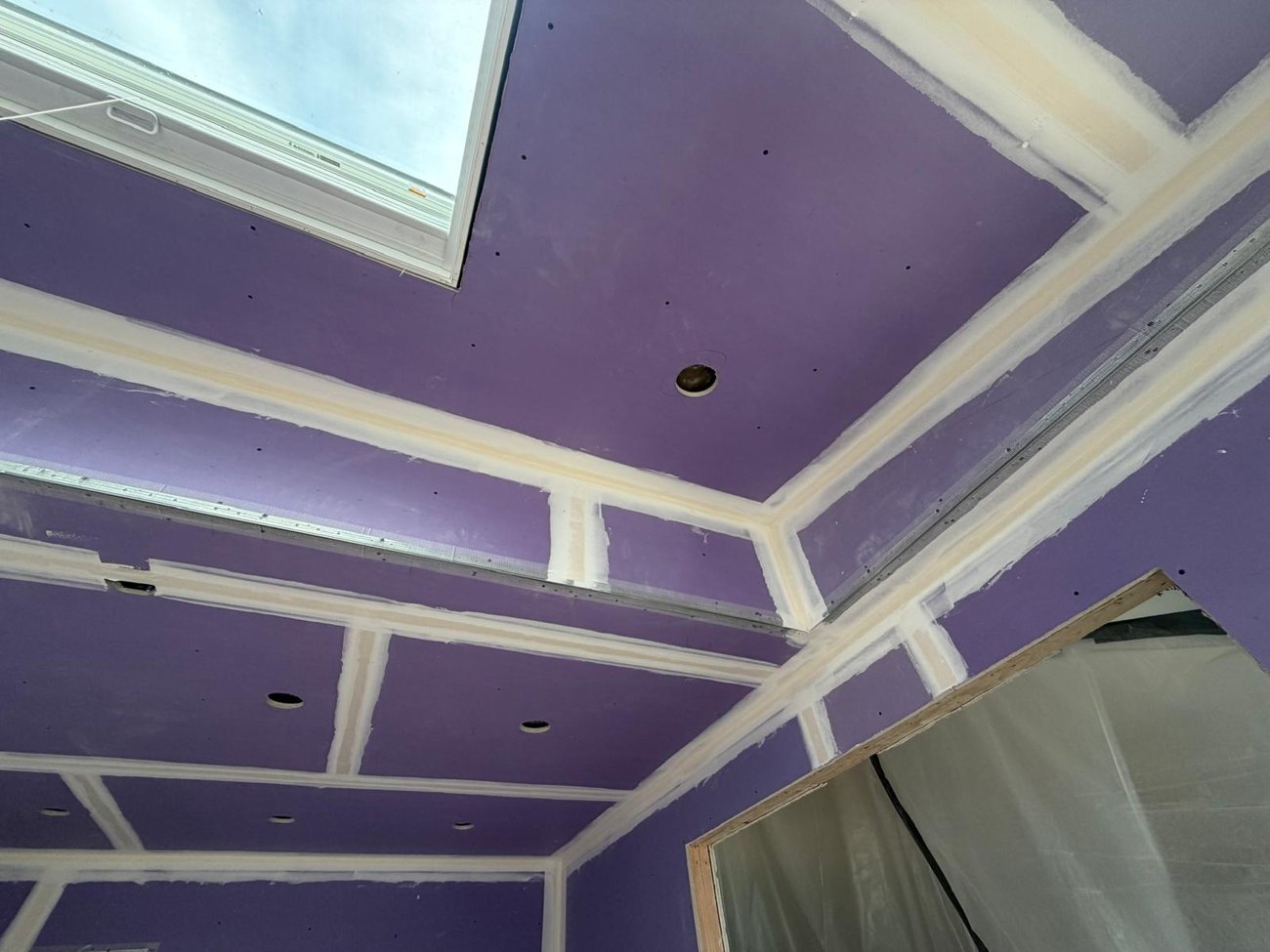 Kitchen walls and ceiling boarded and taped, windows trimmed out next