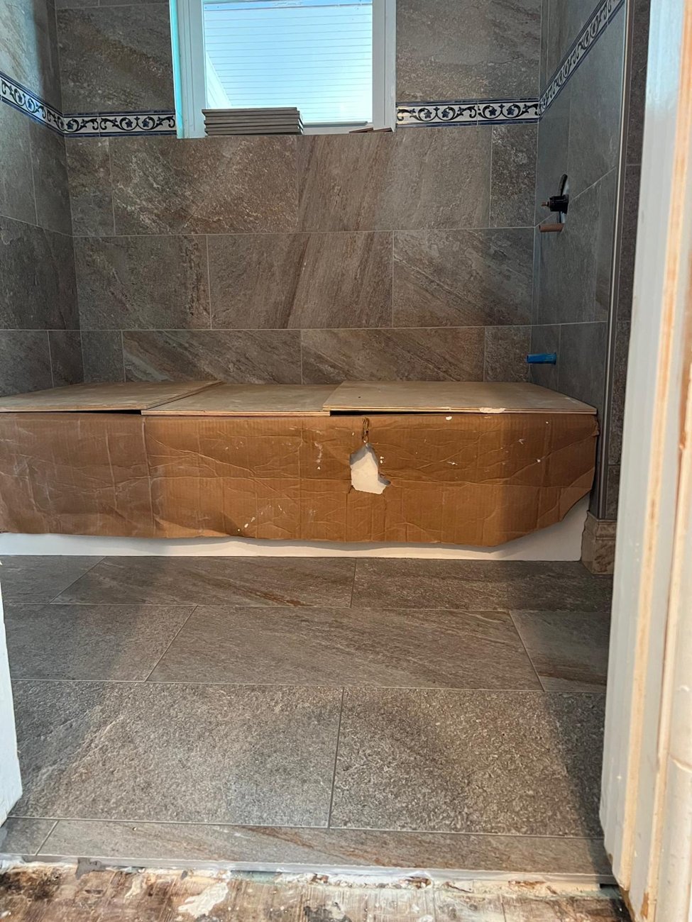 Stone tile bathroom with tub area protected during work