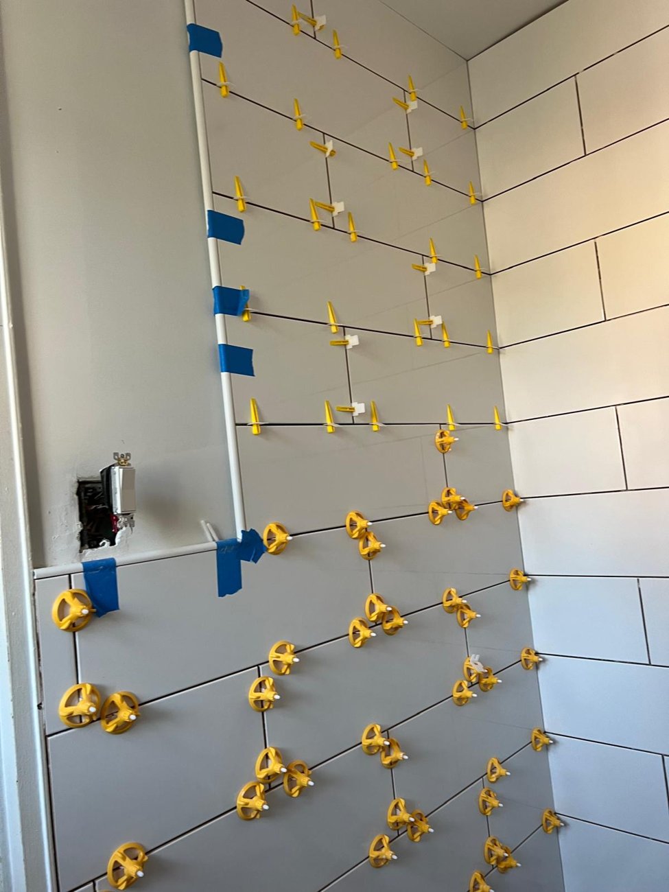 Subway tile install in progress with leveling clips